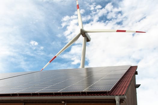 barn covered with solar panels and wind turbine in the background