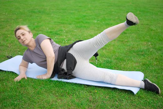 middle aged woman keeping fit with exercises in a park