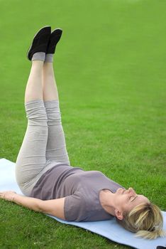 middle aged woman keeping fit with exercises in a park