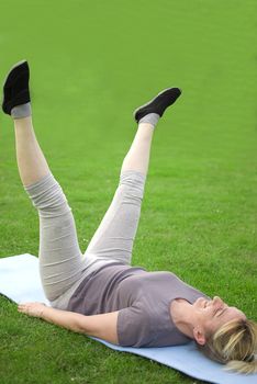 middle aged woman keeping fit with exercises in a park
