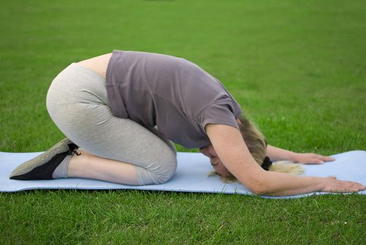 middle aged woman keeping fit with exercises in a park