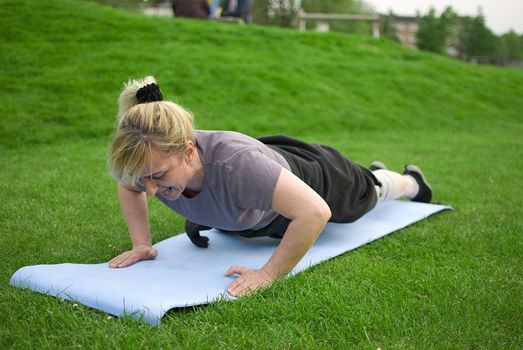 middle aged woman keeping fit with exercises in a park