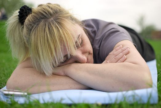 middle aged woman having a rest after exercises in a park