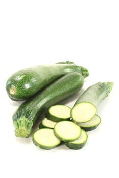 green sliced and whole zucchini on a light background