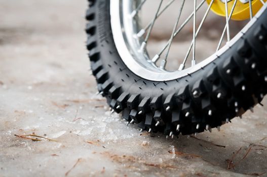Tyre of motocross bike on ice and snow on background, selective focus on the middle part