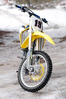 New yellow motocross bike on ice and snow on background