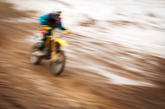 Motocross bike rider in motion with snow on background