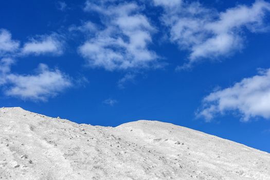 Big pile of freshly mined salt, set against a blue sky