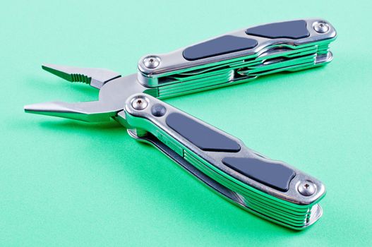 Unfolded multi tool on green background