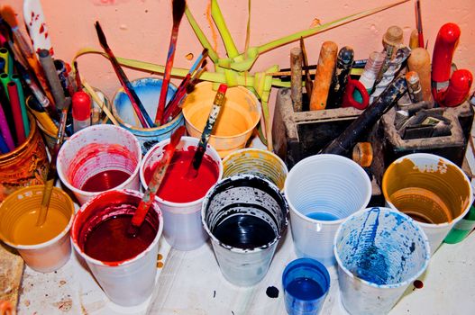 Plastic cups with paint on table in art shop