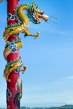 Golden dragon wrapped around red pole, Chinese-style building