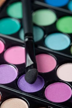 A colorful image on an eyeshadow pallet with a brush.