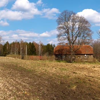 Spring landscape with plowed field and house