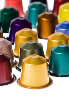 Coffee capsules for a coffee machine, close up view on white reflective background.