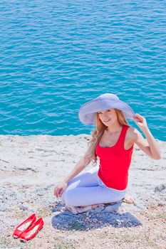 Young and beautiful girl resting on rocks against the sea