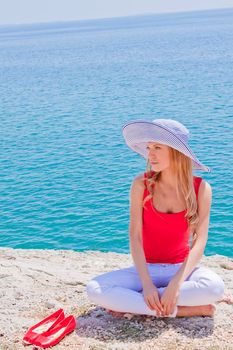 Young and beautiful girl resting on rocks against the sea