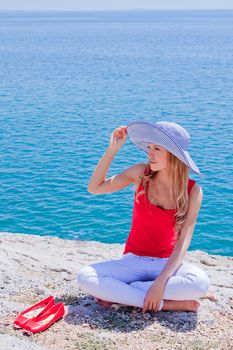 Young and beautiful girl resting on rocks against the sea