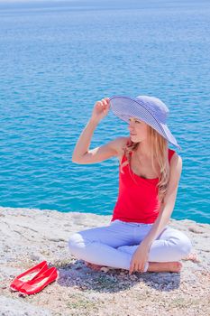 Young and beautiful girl resting on rocks against the sea