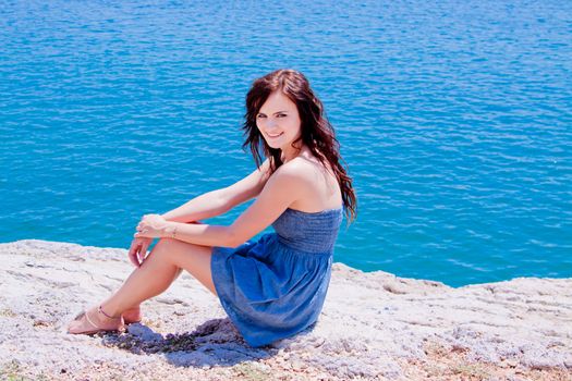 Young and beautiful girl resting on rocks against the sea