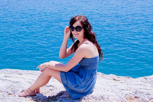 Young and beautiful girl resting on rocks against the sea