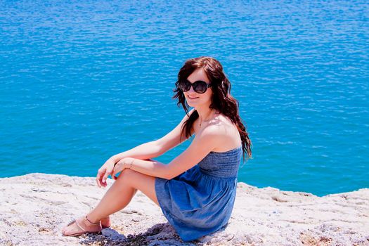 Young and beautiful girl resting on rocks against the sea
