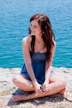 Young and beautiful girl resting on rocks against the sea