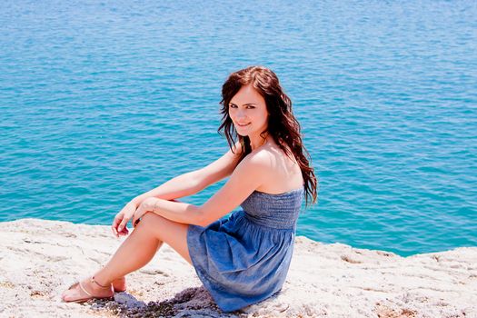 Young and beautiful girl resting on rocks against the sea