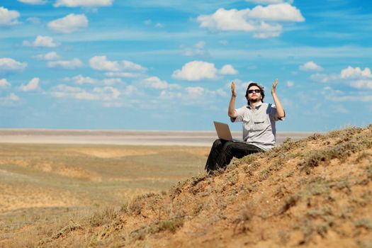 man with laptop praying to the God outdoors
