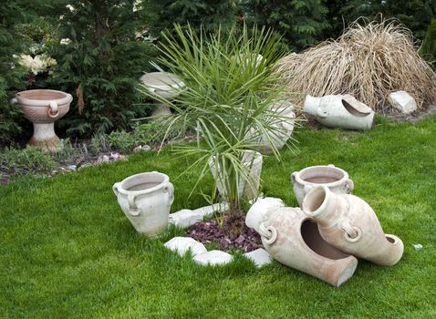 old vases in garden with green grass and palm tree