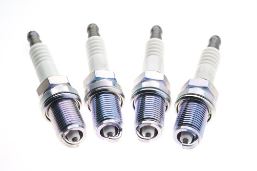 Four spark plugs on a white background