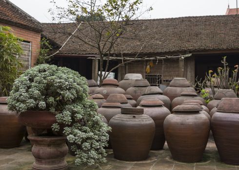 Huge brown stone vases to ferment soy into sauce cover patio.