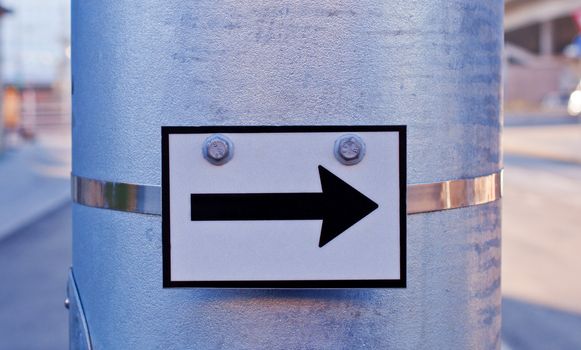 Arrow sign on metal road pole