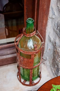Old green bottle in rusty red holder