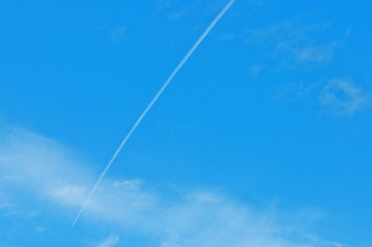 Trace of an airoplane on a cloudy blue sky