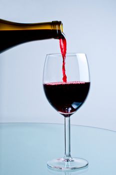 Red wine pouring from bottle into wine glass