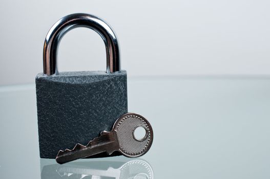 Padlock with a key on grey background