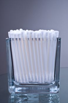 Cotton buds in glass on a glass table
