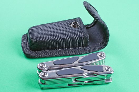 Folded multi tool with case on a green background