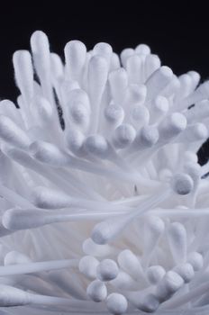 Pile of cotton swabs on black background close up