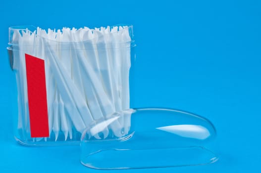 Toothpicks in clear plastic container on blue background