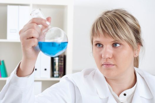 female chemist mixing liquids in test tubes, working in lab