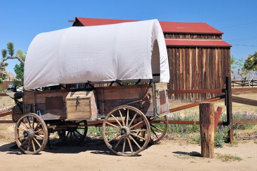 View of a covered wagon and an old rustic barn in Pioneertown, California.