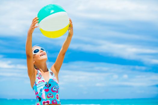 Cute young girl playing with ball on the beach
