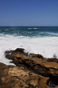 The Pacific Ocean surf breaks upon shoreline rocks at La Jolla, California near San Diego.