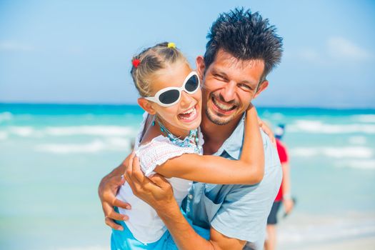 Father and daughter having fun on tropical white sand beach