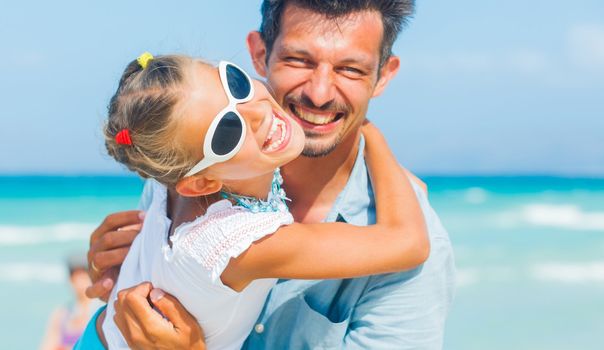 Father and daughter having fun on tropical white sand beach