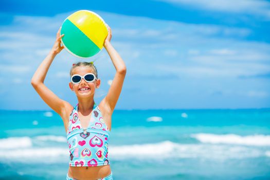 Cute young girl playing with ball on the beach