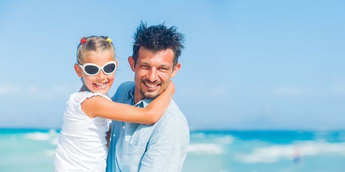Father and daughter having fun on tropical white sand beach