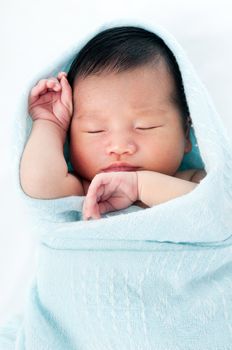 Portrait of a newborn baby wrapped in blanket and sleeping gracefully over white background.