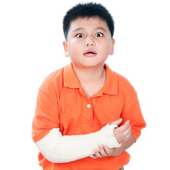 Portrait of a young Asian boy with fractured hand in plaster cast against white background.